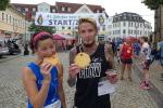 Sabine Börner kann es nicht lassen und verputzt ihre Lorbeeren direkt nach dem Start. Da Stefan Otto mit dem Pokal über den Gesamtsieg auf der Halbmarathondistanz ausreichend Trophäen mit nach Hause nehmen wird, verschenkt er seine frisch gebackene Jakobsmuschel an einen anderen hungrigen Finisher.