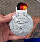 Die Rückseite der Finisher-Medaille  in Berlin ist mit dem Olympiasieger 2016, Eliud Kipchoge aus Kenia geprägt. Er stellte einen neuen Weltrekord in Berlin auf, was diese Medaille zu einer ganz besonderen macht.